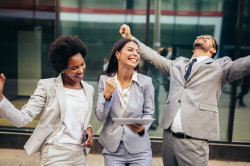 Business team celebrating a triumph, looking at digital tablet.