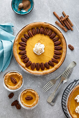Wall Mural - Pumpkin pie with cinnamon, pecan nuts and whipped cream for Thanksgiving, top view.
