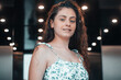© Migue Suarez - Muchacha joven de pelo castaño rizado con vestido de verano saliendo del ascensor para comenzar una reunión de empresa