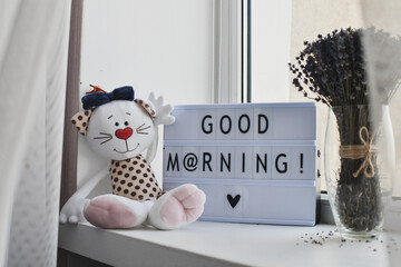 'Good morning' letters inscripted on letterbox standing on window sill. 