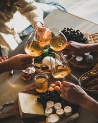 Hands of people clinking glasses with orange or rose wine