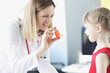 © megaflopp - Pulmonologist doctor holding hormonal inhaler in front of little girl in clinic.