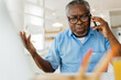 © Astarot - An old black man is sitting at his home office and having a phone conversation with customer support.