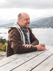 Sticker - Beautiful shot of a middle-aged half bald Caucasian man sitting in a park in front of the l