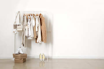 Wall Mural - Rack with stylish clothes, shoes and accessories near light wall