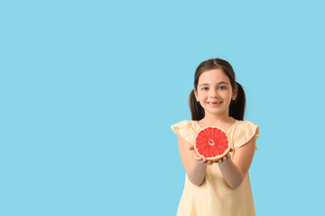 Little girl with fresh tasty grapefruit on color background