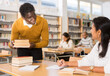 © JackF - Polite friendly african american librarian helping woman find necessary information, giving her books..