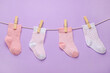 © Pixel-Shot - Different baby socks hanging on rope against color background