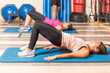 © Iván Moreno - Side view of women doing pelvic exercise with trainer in gym