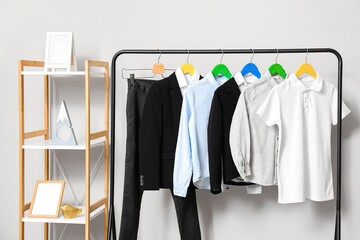 Wall Mural - Rack with stylish school uniform near light wall