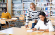 © JackF - Positive young adults communicating while preparing to exam in library