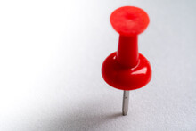 Red Push Pin Stuck In White Floor. Macro Thumbtack Top View. White Background And Copy Space