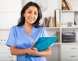 © JackF - Polite latina female health worker meeting patient in medical office, filling out medical form at clipboard