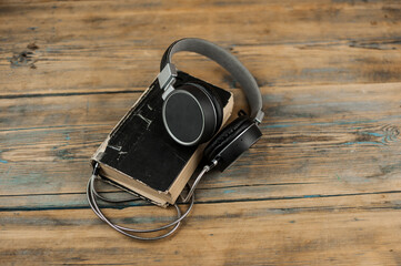 Wall Mural - Audio book concept. Headphones and old book over wooden table. Top view with space for your text