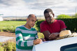 © JackF - Latin american and african men gardeners standing outdoors near car on background with farm field, signing documents.