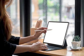 Close-up of a businesswoman hand holding a stylus pen ready to use a tablet blank white screen at the office. Mock up.