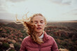 Young woman with closed eyes feeling fresh wind against face standing on mountain hill