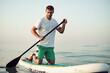 © fotofabrika - Young man in t-shirt and shorts floating on SUP board