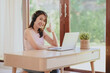 © interstid - Attractive young  Asian woman with hadeset showing thumb up for celebrating an achievement or success while using her laptop working at home