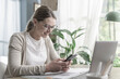 © StockPhotoPro - Woman sitting at desk and connecting with her smartphone