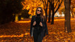 © alones - Fashionable beautiful girl with vintage sunglasses in trendy black clothes with a fashion blazer, sweater and jeans walk in an autumn park with orange fall foliage