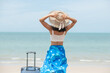 © sutlafk - Beautiful young woman with a hat standing with suitcase on the wonderful sea background, concept of time to travel, with space for your text. Beautiful woman walking with a suitcase on the sunny beach
