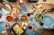 © simona - Group of friends eating together with glass of wine on dining table. Hands taking food from bowl on plate. Group of people enjoying variety of food and drinks at a getogether party