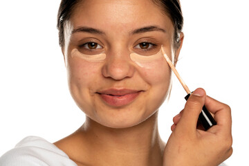 Wall Mural - closeup of a young beautifu smilingl woman applies concealer under her eye