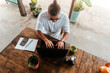 Mężczyzna, cyfrowy nomada pracujący z laptopem i telefonem przy stoliku w kawiarni, praca zdalna podczas podróży.