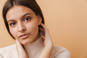 Wall Mural - Young woman touching her face and looking at camera