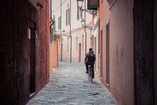 A Man Driving A Bike Down A Italian Alley From The Back
