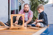 © ADDICTIVE STOCK - Father with son measuring wooden pieces with tape