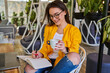 © Тарас Нагирняк - Happy smiling beautiful woman sitting and drinking coffee with notebook