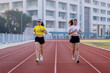 © EduLife Photos - Two young Asian women in sports outfits jogging on running track in city stadium in the sunny morning for a healthy lifestyle. Young fitness women run on the stadium track.