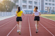 © EduLife Photos - Two young Asian women in sports outfits jogging on running track in city stadium in the sunny morning for a healthy lifestyle. Young fitness women run on the stadium track.