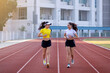 © EduLife Photos - Two young Asian women in sports outfits jogging on running track in city stadium in the sunny morning for a healthy lifestyle. Young fitness women run on the stadium track.