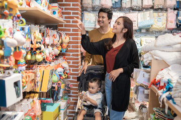 Canvas Print - father and mother shopping at the baby shop with their son in the stroller