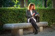 © Ricardo MzF .com  - Mature woman in her 50's with curly red hair and white skin with freckles business executive with mobile phone in meeting , smiling  with briefcase in a park