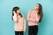 © luismolinero - Little sisters girls isolated on blue background thinking an idea while scratching head