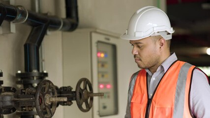 Wall Mural - Young asian engineer working at valve water pump checking and maintenance for the safety. Worker using tablet to control the system water of the building.
