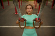 High angle view of a sporty determinate middle aged African American, mixed race woman doing arm exercises with suspension straps while performing an outdoor cross training in the sportsground