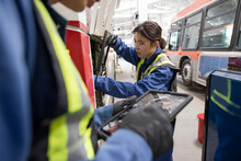 Female Mechanic Fixing Bus Engine In Maintenance Facility