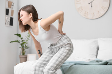 Sticker - Young woman suffering from back pain in bedroom