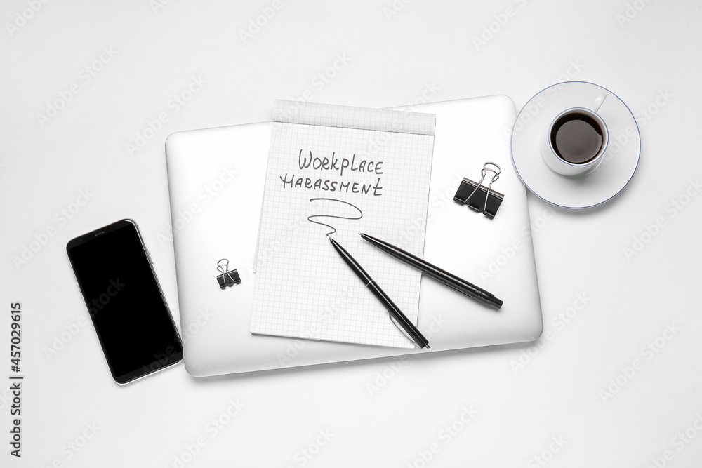 Stationery with text WORKPLACE HARASSMENT, cup of coffee and gadgets on white background