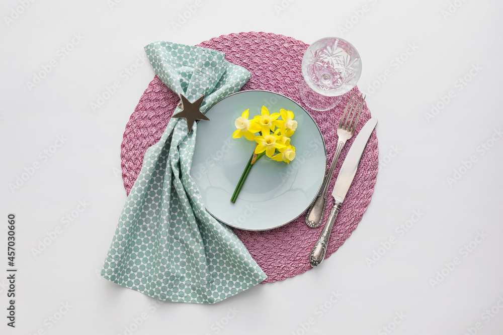 Beautiful table setting with narcissus flowers on white background