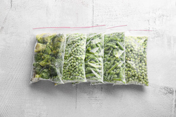 Wall Mural - Plastic bags with different frozen vegetables on grey background