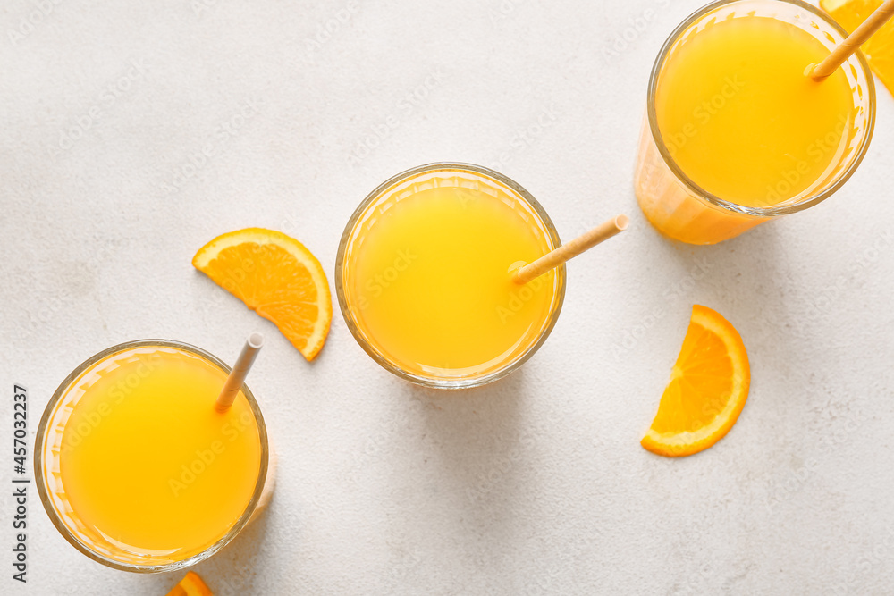 Glasses of tasty orange juice on light background