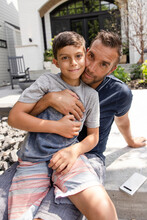 Portrait Confident Father And Son Hugging On Patio