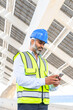 © ADDICTIVE STOCK - Ethnic supervisor in hardhat with smartphone against solar power station