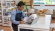© Ron - Young male owner is checking his stocks and goods in his startup bakery or café shop at the end of the day with light flair from the window. Young entrepreneur working on his account and coming orders